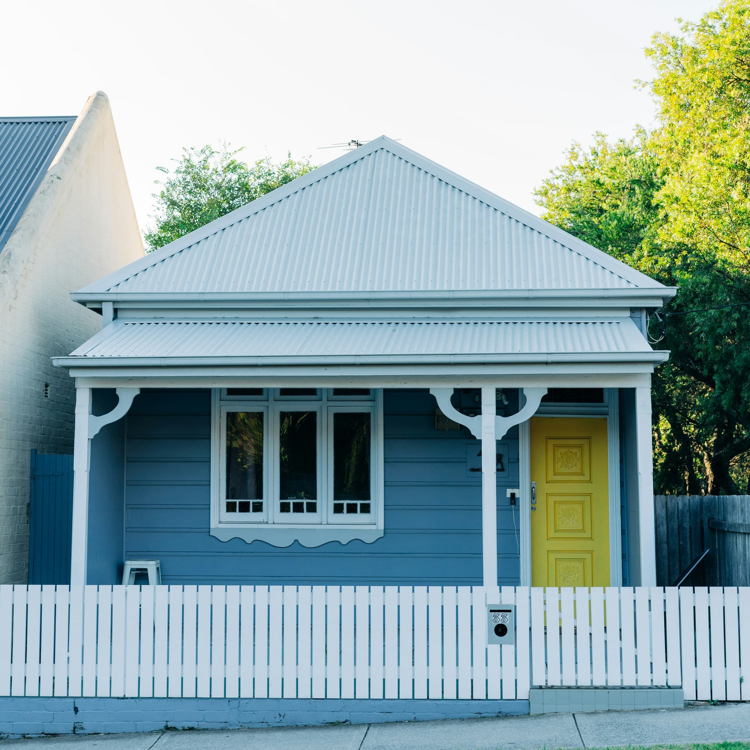 Classic Australian Federation cottage with blue weatherboard, yellow door, and white picket fence