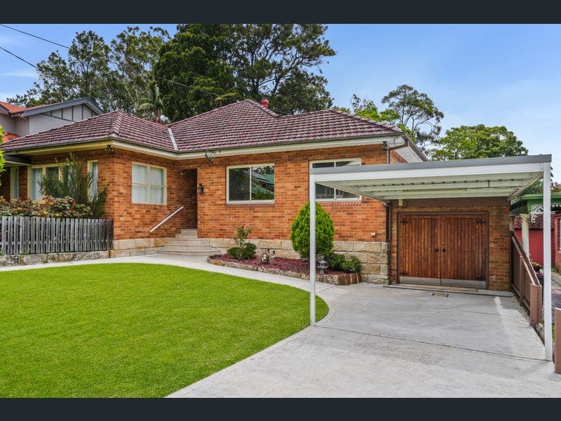 Classic Australian brick suburban home with green lawn and carport